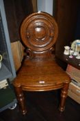 A Victorian stained oak hall chair, having round back with carved scrolls to sides.