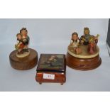 Two vintage Hummel figurines having musical movements incorporated and a similar music box.