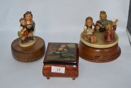 Two vintage Hummel figurines having musical movements incorporated and a similar music box.