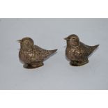 A pair of salt and pepper pots in white tone metal in the form of birds, one with broken hinge.