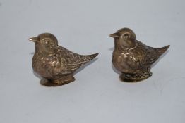 A pair of salt and pepper pots in white tone metal in the form of birds, one with broken hinge.