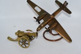 A vintage brass bomber on stand and a model cannon.