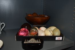 A trio of paperweights, a turned wooden bowl containing fruit and six natural stone eggs, incluing