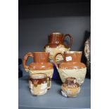 A collection of earthen ware jugs having relief designs, including hall marked silver edged examples