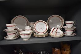 A collection of Queen Anne bone china, having white ground with red band gilt leaf detailing.