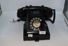 A mid century black rotary telephone.