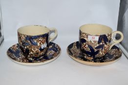 Two 19th century oversized cups and saucers, having floral pattern in blue and rust tones,