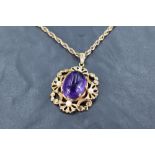 An amethyst cabochon pendant having seed pearl decoration to scrolled 9ct gold mount on a 9ct gold