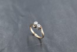 A two stone diamond ring, total approx 0.25ct in claw set mounts with crossover shoulders on a 9ct