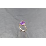 A baguette cut heat treated amethyst ring in a four claw setting on a 9ct gold loop, size R & approx
