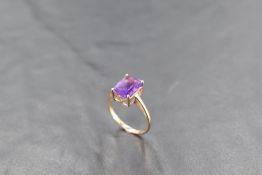 A baguette cut heat treated amethyst ring in a four claw setting on a 9ct gold loop, size R & approx