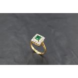 An 18ct gold, emerald and diamond ring, the central raised square-cut emerald totalling 0.75cts