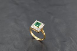 An 18ct gold, emerald and diamond ring, the central raised square-cut emerald totalling 0.75cts