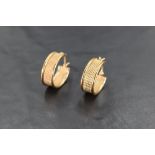 A pair of 9ct gold earrings, of oval form with textured surface, with hinged and curved pin for