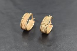 A pair of 9ct gold earrings, of oval form with textured surface, with hinged and curved pin for