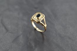 A 9ct gold sapphire and diamond ring, having a central raised oval-cut sapphire within a rubbed-over