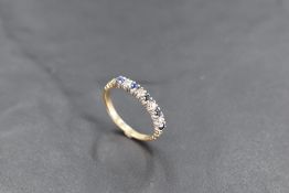 A diamond and sapphire half eternity ring having moulded shoulders and a 9ct gold loop, size K &