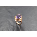 An amethyst ring having a yellow metal miligrain set collared mount on a yellow metal loop stamped