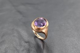 An amethyst ring having a yellow metal miligrain set collared mount on a yellow metal loop stamped