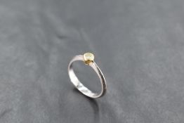 A diamond solitaire ring, approx 0.075ct in a yellow gold collared mount on an 18ct white gold loop,
