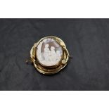 A large Victorian conch shell cameo brooch depicting a courting couple scene with cupid