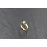 An emerald and diamond three stone ring in a claw set stepped mount on an 18ct gold loop, size K &