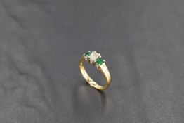 An emerald and diamond three stone ring in a claw set stepped mount on an 18ct gold loop, size K &