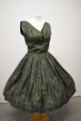 A 1950s green pure silk patterned day dress, having cross over bust and cummerbund style waist