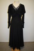 A 1930s Art Deco black evening gown having full length sleeves with lace and self covered buttons to