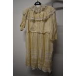 An Edwardian child's dress of cream silk and lace, with pin tucks to hem and smocked sleeves.