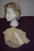 A Victorian lace bonnet having decorative floral ribbon detail and a lace cap with silk ribbon to