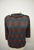 A 1960s dead stock jumper, having abstract atomic type pattern in red and black on forest green