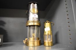 An early 20th century Petterson coal mining safety lamp with a similar miniature brass lamp.