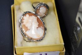 A vintage ladies dress ring and brooch having cameo cut designs with white metal mounts