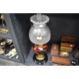 A fine Victorian oil lamp having ceramic and brass base with cranberry glass well and formed