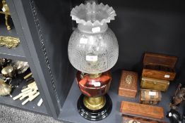 A fine Victorian oil lamp having ceramic and brass base with cranberry glass well and formed