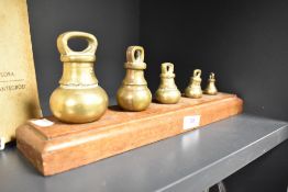 A set of graduated brass kitchen scale weights.