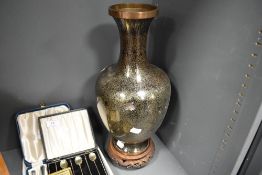 A Japanese Cloisonne enamel vase having black ground, with yellow metal wire. On carved wooden base.