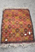A vintage hand woven Afghan wool rug in red and brown grounds with a floral pattern with fringing