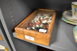 A wooden case full of vintage beads, predominantly coloured glass.