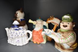 Four novelty tea pots including Tony Wood cat design, a Coronation deaf man and the village