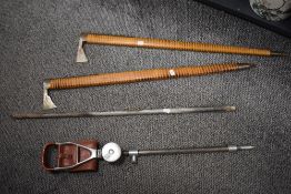 A vintage shooting stick and two ceremonial axes or similar having wooden handles with brass
