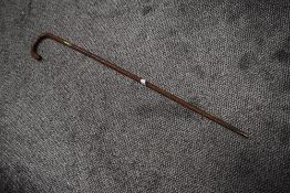 An antique textured wood walking cane having silver cuff to shaft and silver pips to handle.