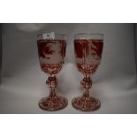 Two Victorian oversized Bohemian ruby overlay goblets, having finally executed wheel engraved scenes