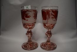 Two Victorian oversized Bohemian ruby overlay goblets, having finally executed wheel engraved scenes