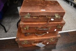 Four early 20th century graduated leather suitcases