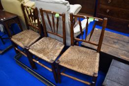 A set of three 19th Century stained frame spindle back kitchen chairs having rush seats , of