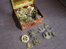 A tin box of mainly military Cap Badges including Cameron, Military Police, Manchester, Royal
