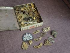 A tin box of mainly Military Cap Badges including 4th Border Cumberland & Westmoreland Regiment,