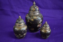 Three graduated lidded brass urns, having enamel detailing.